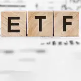 Holzwürfel mit den Buchstaben "ETF" stehen auf Finanzdokumenten. Ein ETF Sparplan ist eine einfache Möglichkeit, langfristig Vermögen aufzubauen.