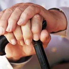 Hände eines Rentners halten einen Gehstock. Mögliche Werbungskosten für Rentner.