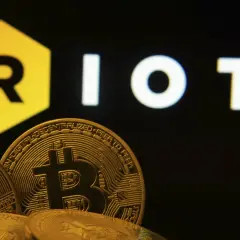 Goldene Bitcoin-Münzen vor dem "RIOT"-Logo. Die Riot Platforms Aktie im Fokus der Kryptowelt.