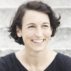 Lachende Frau mit kurzen Haaren, die an Madame Moneypenny Kritik erinnert.