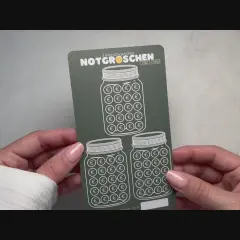 Hände halten eine "Notgroschen Challenge"-Karte mit drei Einmachgläsern, gefüllt mit Euro-Symbolen. Perfekt, um die eigene spar challenge selber machen zu starten!