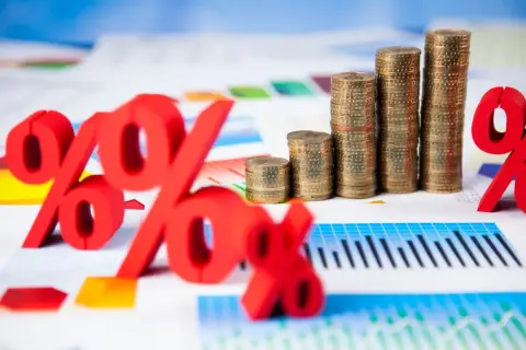 Rote Prozentzeichen und Münzstapel auf Finanzdiagrammen. Sie fragen sich, was sind Zinsen? Hier sehen Sie die Antwort visuell dargestellt.