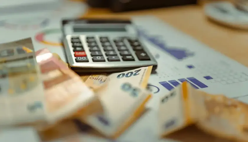 Rechner und Euro-Scheine liegen auf einem Finanzbericht. Eine Witwe überlegt ihre Steuerklasse.