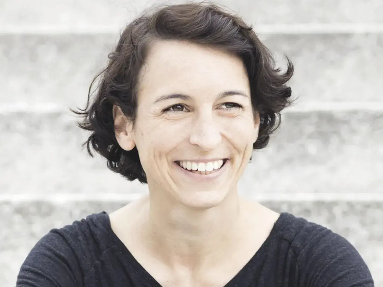 Lachende Frau mit kurzen Haaren, die an Madame Moneypenny Kritik erinnert.