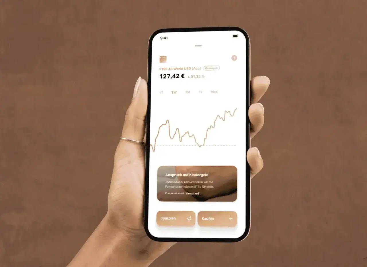 Hand h&auml;lt Smartphone mit Trade Republic App. Ein FTSE All World ETF mit Sparplan-Option wird angezeigt.