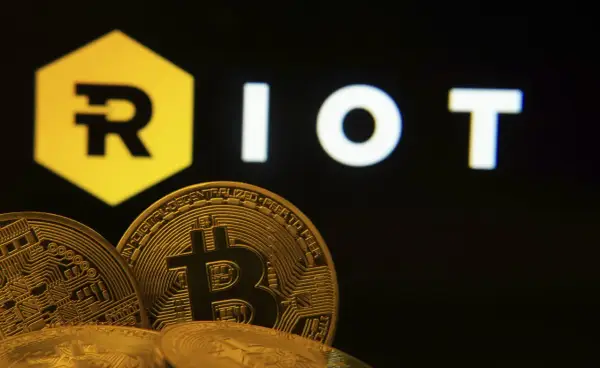 Goldene Bitcoin-Münzen vor dem "RIOT"-Logo. Die Riot Platforms Aktie im Fokus der Kryptowelt.